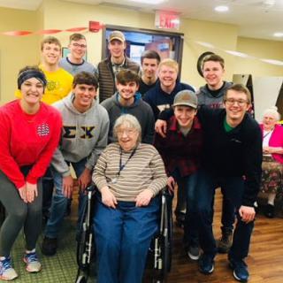 A heartwarming moment with an elderly woman surrounded by young men during a community gathering.