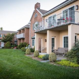 A view of residential apartments with balconies overlooking a well-maintained garden and lawn.
