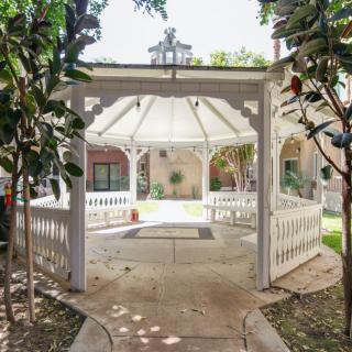 A charming white gazebo in a garden setting surrounded by trees.