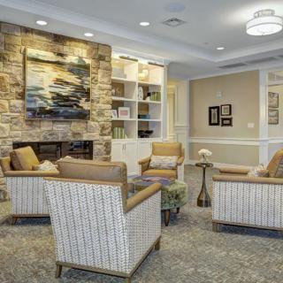 A cozy living room with a seating arrangement around a fireplace, featuring artwork and elegant decor.