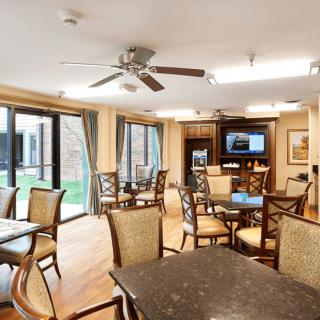 A well-lit dining area with tables, chairs, and a television.