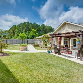 A well-maintained backyard with a pergola, outdoor seating, and a lush lawn.