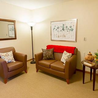 A cozy living room with two chairs, a floor lamp, and wall decor.