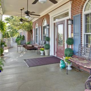 A spacious porch with elegant decor, featuring ceiling fans, potted plants, and comfortable seating.