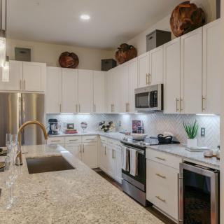 A modern kitchen featuring white cabinets, stainless steel appliances, and a granite countertop with decorative vases on top.