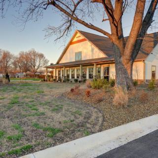 A charming house with a spacious porch surrounded by trees at sunset.