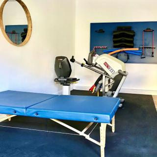 A physical therapy room equipped with a treatment table and exercise machine.
