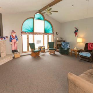 A spacious living room with high ceilings, featuring a large arched window and decorated in a patriotic theme.