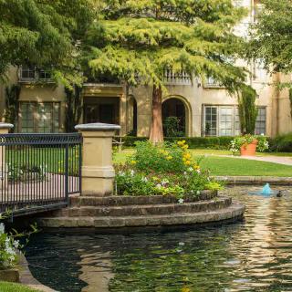 A landscaped garden with a pond and small bridge in an apartment complex.