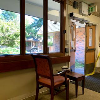 A cozy waiting area with a chair and a view of the outdoors through large windows.