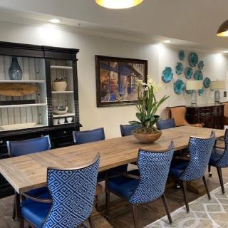 A stylish dining room featuring a wooden table with blue chairs, elegant wall art, and decorative accents.