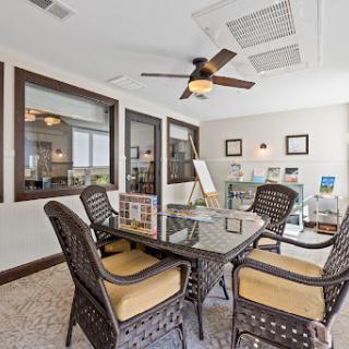 A modern office space featuring a glass table and comfortable seating, illuminated by natural light.