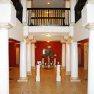 A spacious foyer featuring classic architectural elements with columns and a balcony.