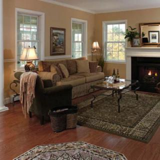 A cozy living room with a sofa, coffee table, and a lit fireplace.