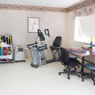 A multifunctional room featuring exercise equipment and a workspace.