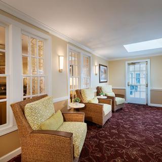 A cozy seating area with wicker chairs and a patterned carpet, featuring warm lighting and large windows.