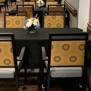 A dining area with patterned chairs and a table adorned with a floral centerpiece.