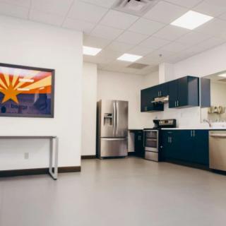 A modern kitchen interior featuring dark blue cabinets, a stainless steel refrigerator, and stylish artwork on the wall.