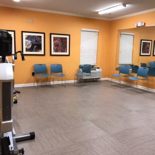 An empty waiting room with orange walls, modern chairs, and artwork on the walls.