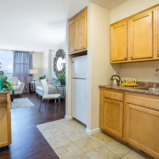 A cozy apartment featuring a compact kitchen and a well-lit living room with modern furnishings.