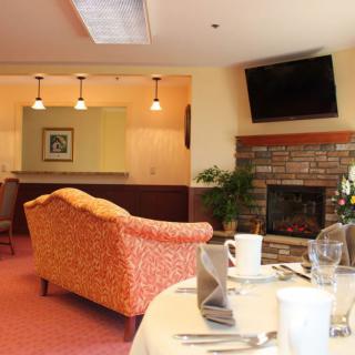 A cozy living and dining area featuring a fireplace, wall-mounted television, and a table set for dining.