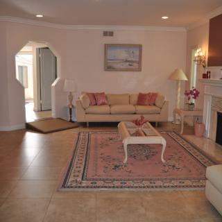 A cozy living room with sofas, a coffee table, and a fireplace, featuring elegant decor and soft lighting.