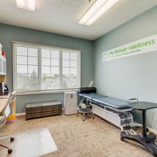 A clean and organized medical exam room with a treatment table and large windows.