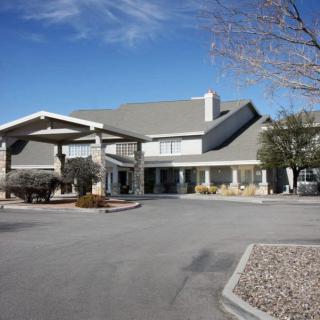 A hotel entrance with a driveway under a clear blue sky.