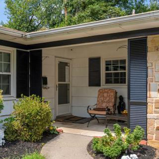 A cozy house porch with a chair, surrounded by a small garden.
