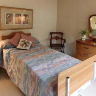 A cozy bedroom with a single bed, colorful quilt, and wooden furniture.
