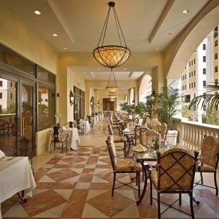 Elegant outdoor dining area with chandeliers and patterned tile flooring.