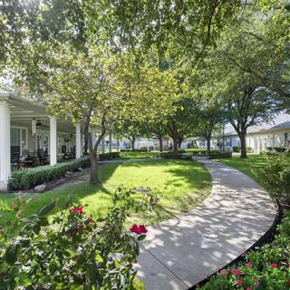 A serene garden pathway surrounded by lush greenery and flowering plants.