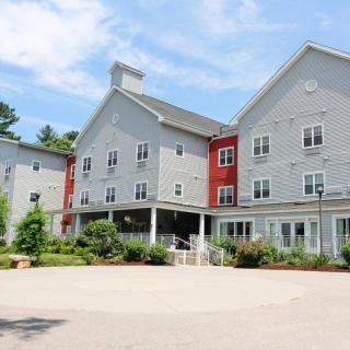 A modern residential building with a gray and red exterior under a blue sky.