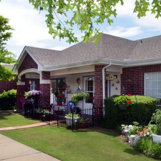 A charming brick house with a neatly landscaped front yard and flower-filled porch.