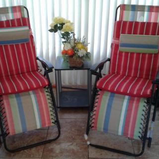 Two striped reclining chairs with a small table and floral arrangement.