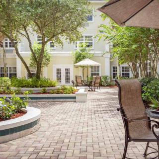 A peaceful courtyard featuring a landscaped garden with outdoor seating and umbrellas.