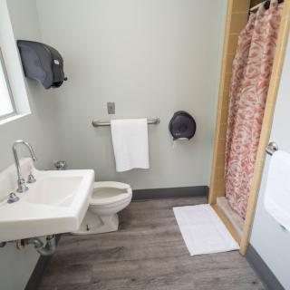 A clean, accessible bathroom with a sink, toilet, and shower area.