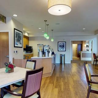 A modern kitchen and dining area with elegant lighting and wood flooring.