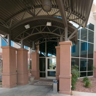 A modern building entrance with a covered walkway and large glass windows.