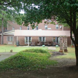 A brick house with a backyard patio and surrounding trees.