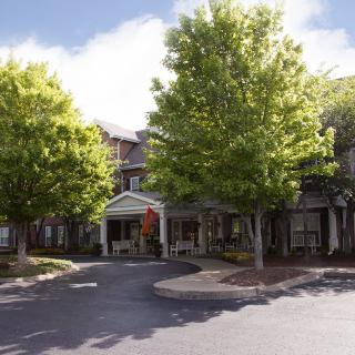 A charming building exterior surrounded by lush trees under a clear sky.