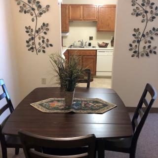 A cozy dining area with a wooden table, chairs, and kitchen in the background.