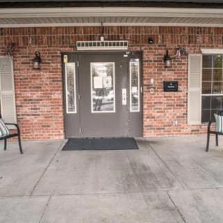The entrance of a brick building with chairs on either side.