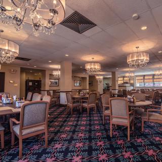 A cozy restaurant interior with elegant chandeliers and neatly arranged tables and chairs.