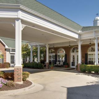 Entrance of a building with columns and landscaping.