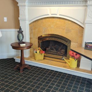 A cozy living room with a decorative fireplace and a wooden side table adorned with flowers.