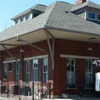 A historic brick train station with an overhanging roof.