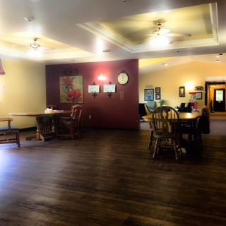 A spacious dining area with wooden tables and chairs, featuring warm lighting and ceiling fans.