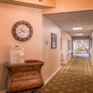 A carpeted hallway with a decorative clock and furniture.