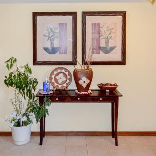 A decorated console table with artwork, a vase, and a potted plant.